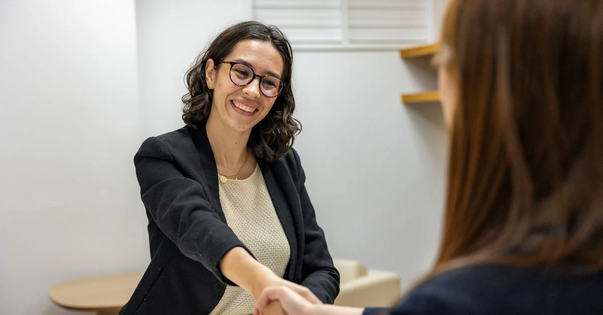 Des femmes d'affaires se serrant la main dans un bureau, représentant un entretien d'embauche ou un partenariat réussi.