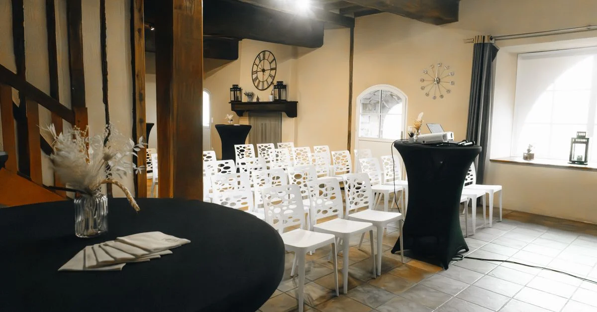 Charmant lieu intérieur avec des chaises blanches, une décoration élégante et une ambiance rustique, parfait pour des événements intimes.
