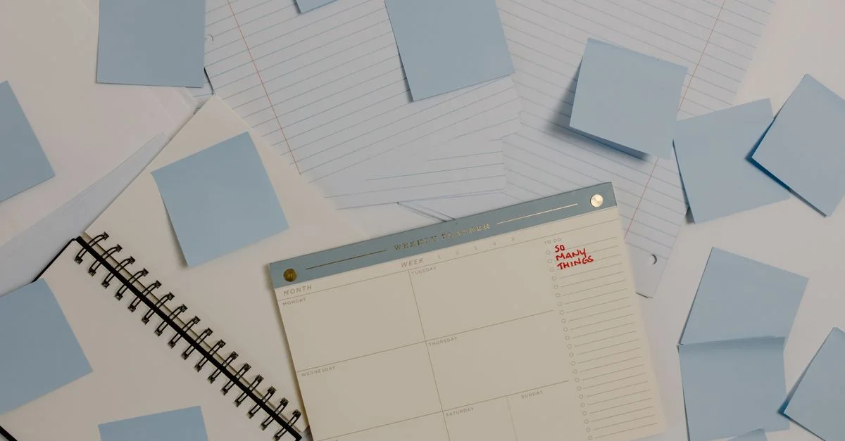 Vue de dessus d'un bureau avec un planificateur, des notes autocollantes et des papiers lignés pour une organisation.