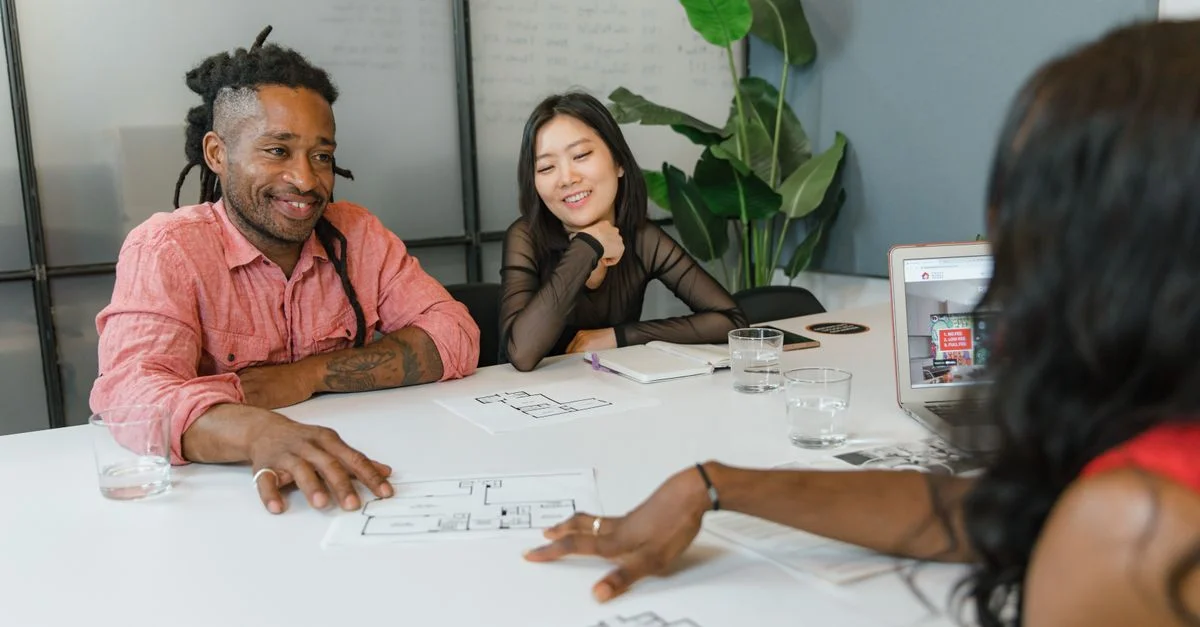 Un groupe diversifié de collègues participant à une session de planification avec des plans architecturaux dans un bureau moderne.