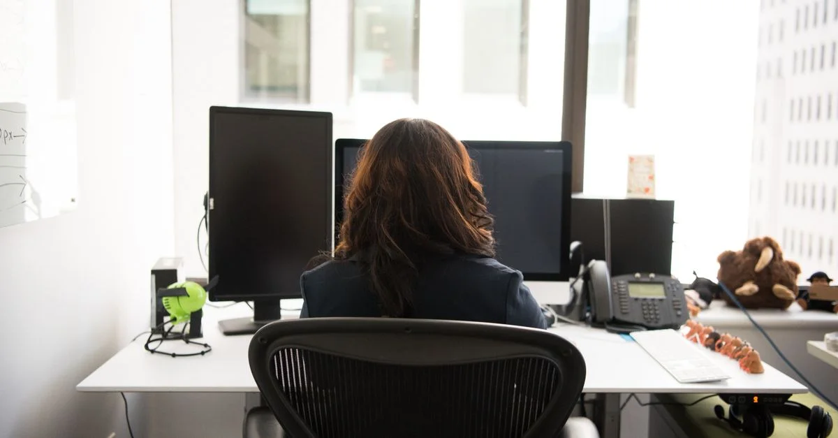 Femme travaillant sur un bureau dans un bureau moderne avec technologie et vue sur la ville.
