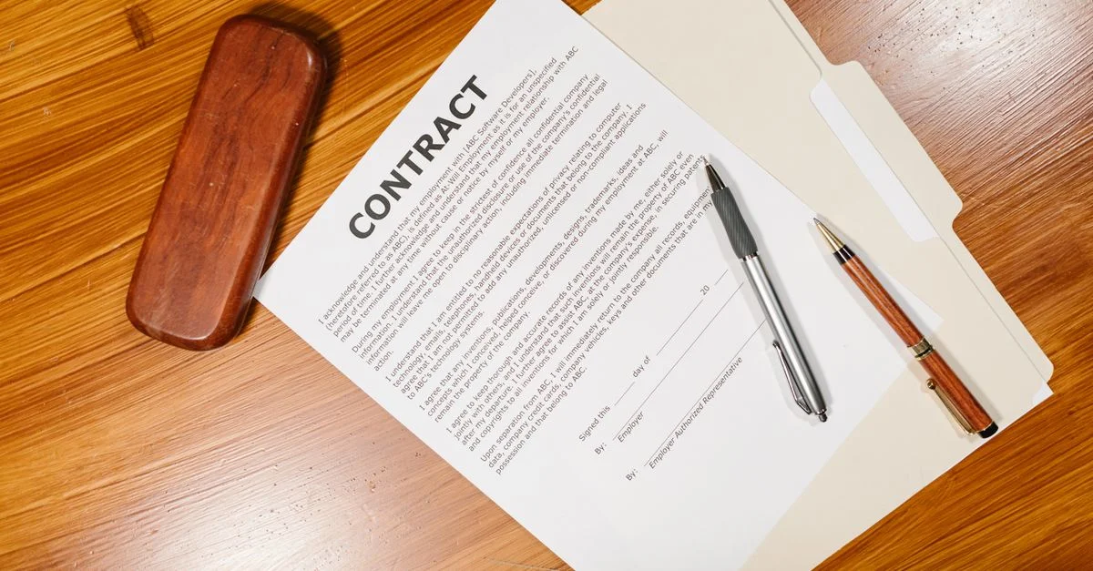 Vue en plongée d'un document de contrat avec des stylos et un étui sur une table en bois.