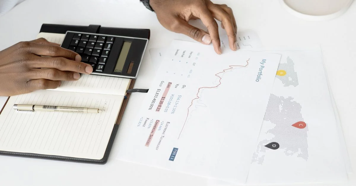 Vue de dessus d'une personne analysant des documents financiers à l'aide d'une calculatrice pour la planification des investissements.