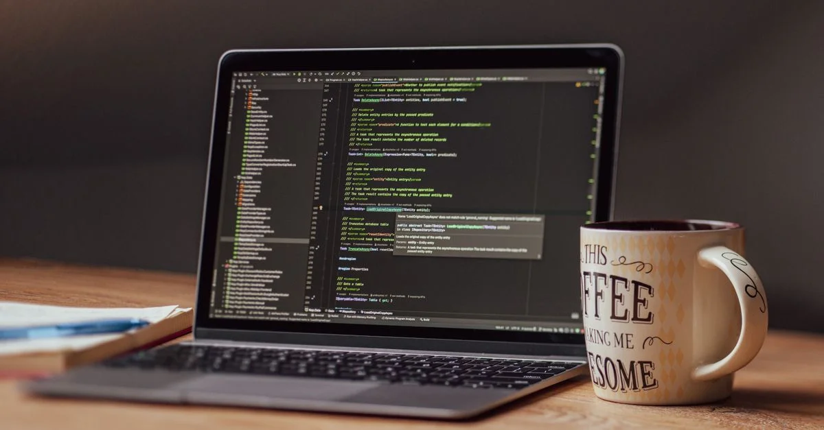 Ordinateur portable affichant un éditeur de code avec une tasse de café sur le bureau, parfait pour les thèmes technologiques.