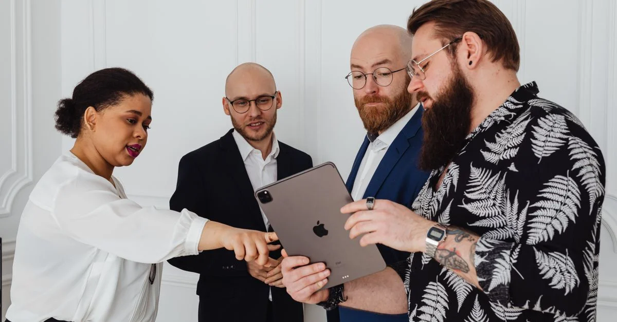 Un groupe de professionnels divers discutant d'un projet en utilisant une tablette dans un bureau moderne.